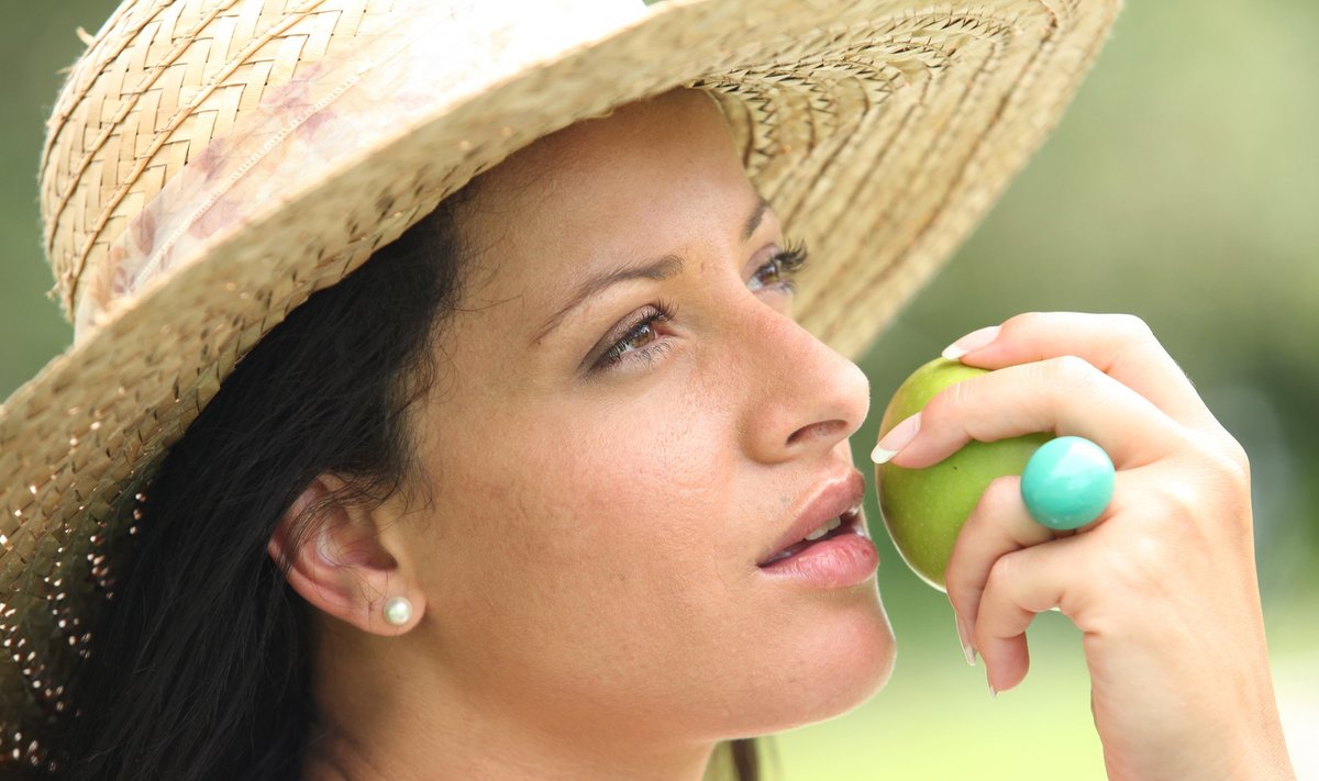 Woman in a straw hat about to bite an apple