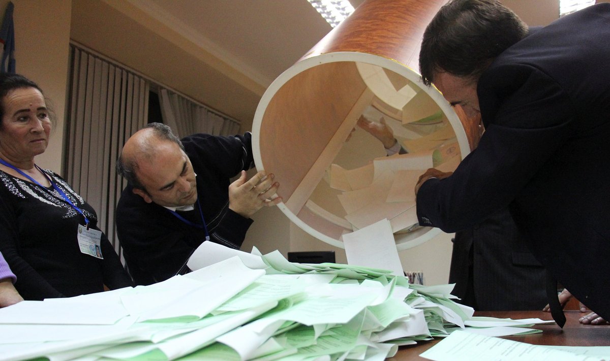 Members of local electoral commission empty ballot box after presidential election in Tashkent