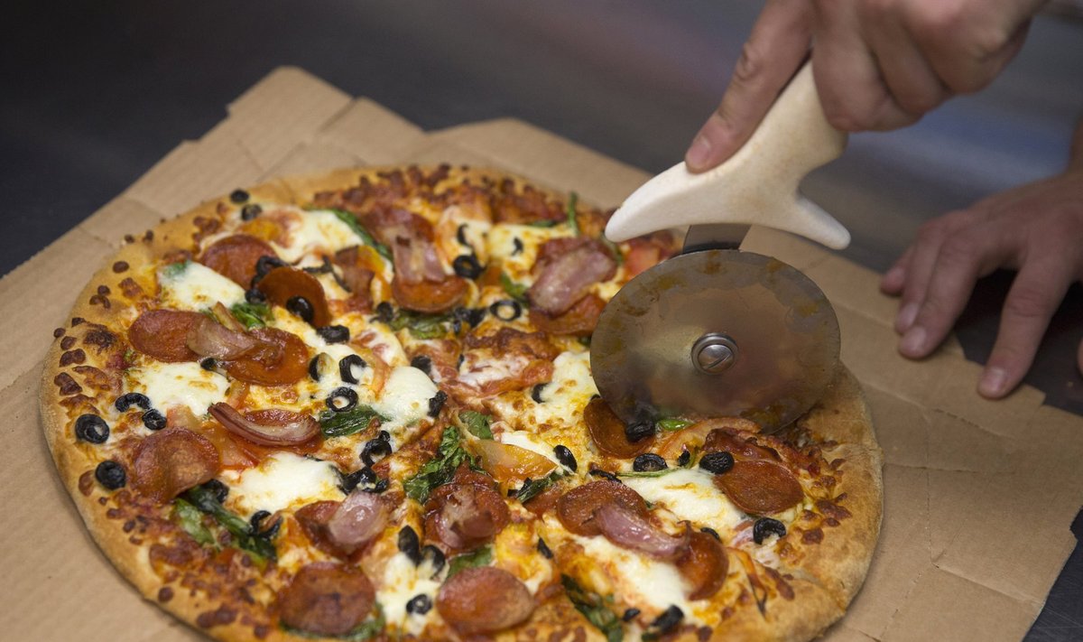 Berliinis asuva Domino's Pizza töötaja lõikab pitsat lahti.