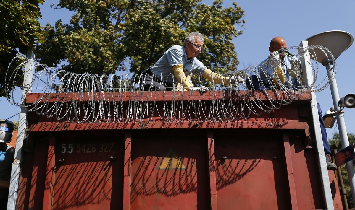Prison guards attach barbwire on a freight train wagon, prepared to seal the border fence in Hungary at the train station in Roszke