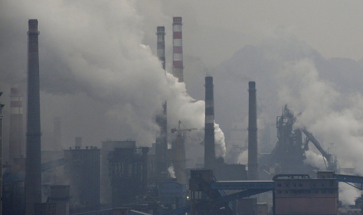 Smoke rises from chimneys and facilities of steel plants on a hazy day in Benxi