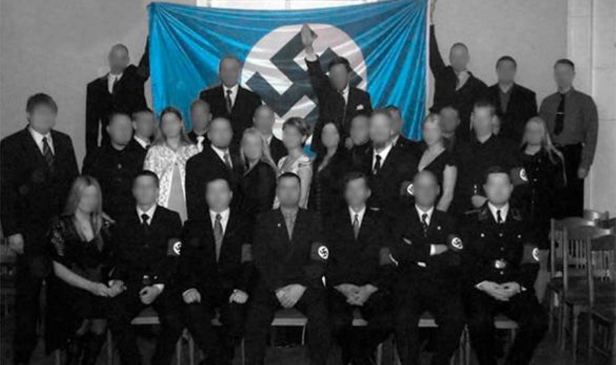 30 inimest poseerib Adolf Hitleri sünniaasta päeval 2007 sinimustvalge haak ristilipu all, kuigi osa neist ei saanud aru, mida see lipp tähendab. Pildid Teinoneni veebiküljelt, kus ta on osalejate näod kinni katnud. (www.kaitsepolitsei.com)
