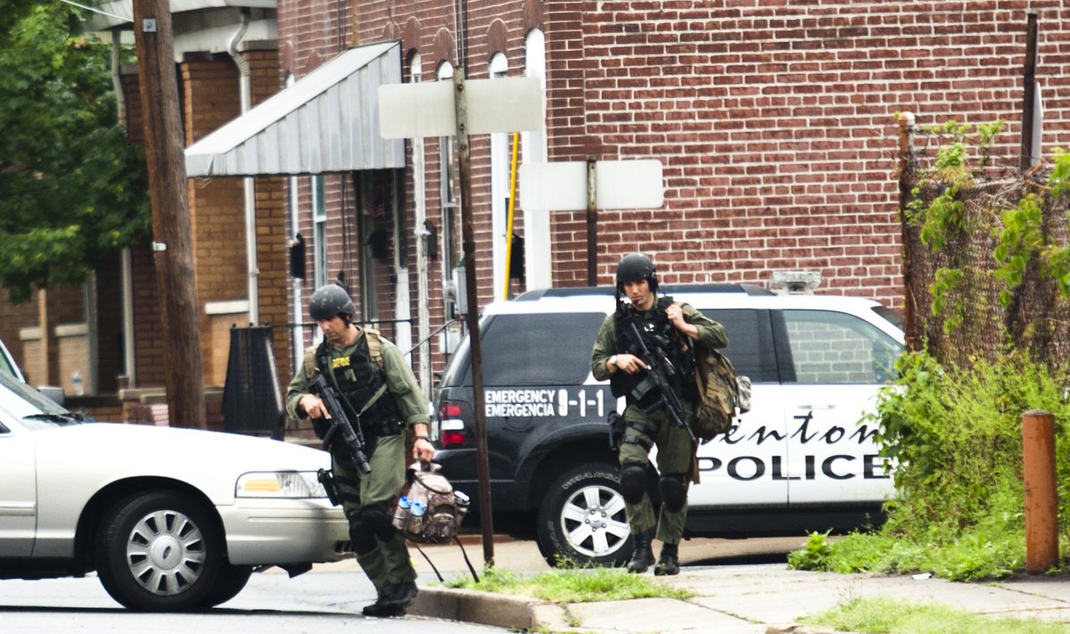 SWAT police personnel walk near a house, where a gunman suspected of killing his wife is barricaded in, in Trenton