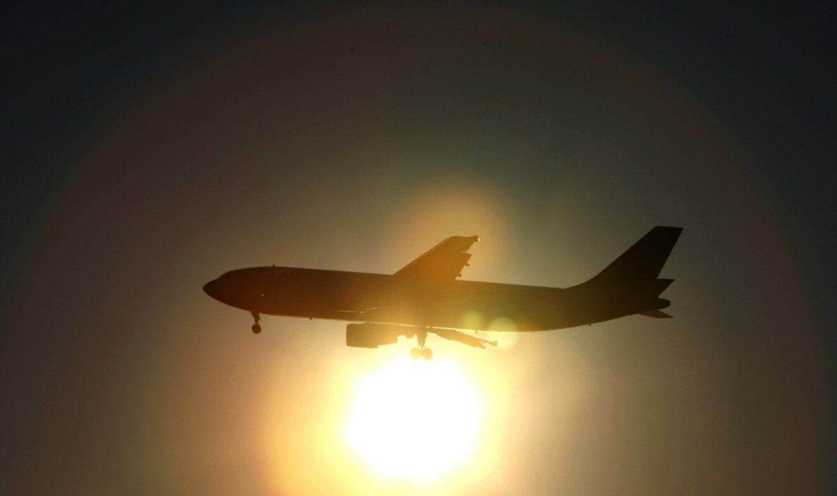 A Japan Airlines aircraft is silhouetted against the setting sun as it prepares to land at Haneda airport in Tokyo