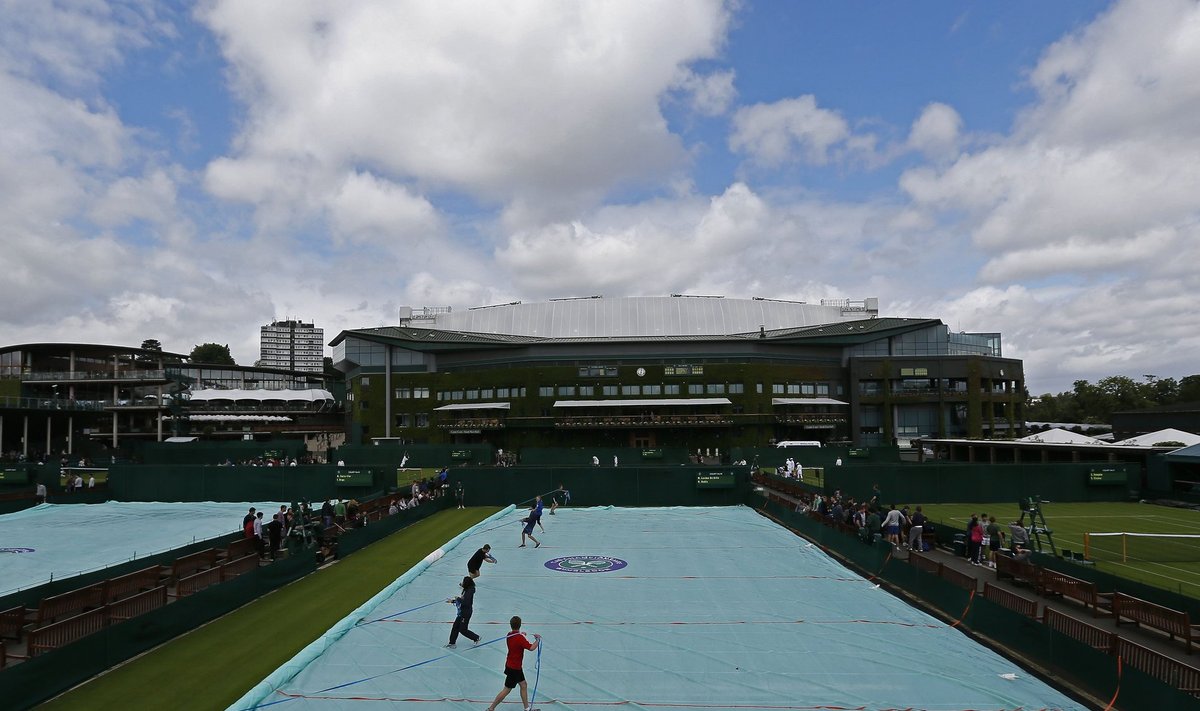 Ground staff practise covering a court at Wimbledon in London