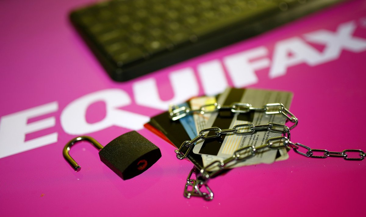 Credit cards, a chain and an open padlock is seen in front of displayed Equifax logo in this illustration