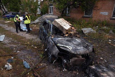 Эксперты полиции работают рядом с разрушенным автомобилем возле промышленной зоны в Киеве после массированного ночного ракетного удара по Украине. В результате обстрела по всей стране были убитые и раненые.