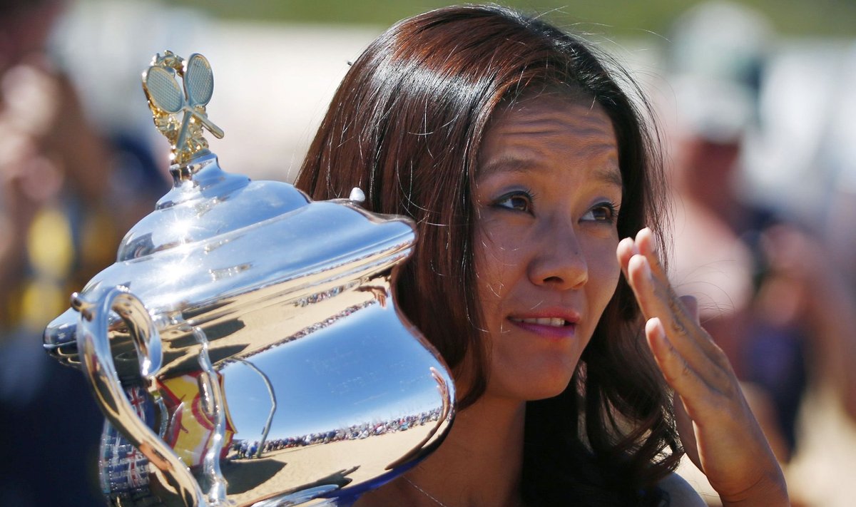 Li Na of China swats a fly as she poses with her Australian Open trophy during a photo call in Melbourne
