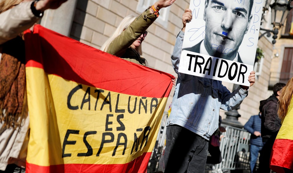 „Kaabakas,” on kirjutatud plakatile, millel peaministrile on joonistatud Hitleri vuntsid. Ühtaegu hoiavad parempartei Vox toetajad lippu kirjaga „Kataloonia on Hispaania” ja on tõstnud käe fašistlikuks tervituseks.