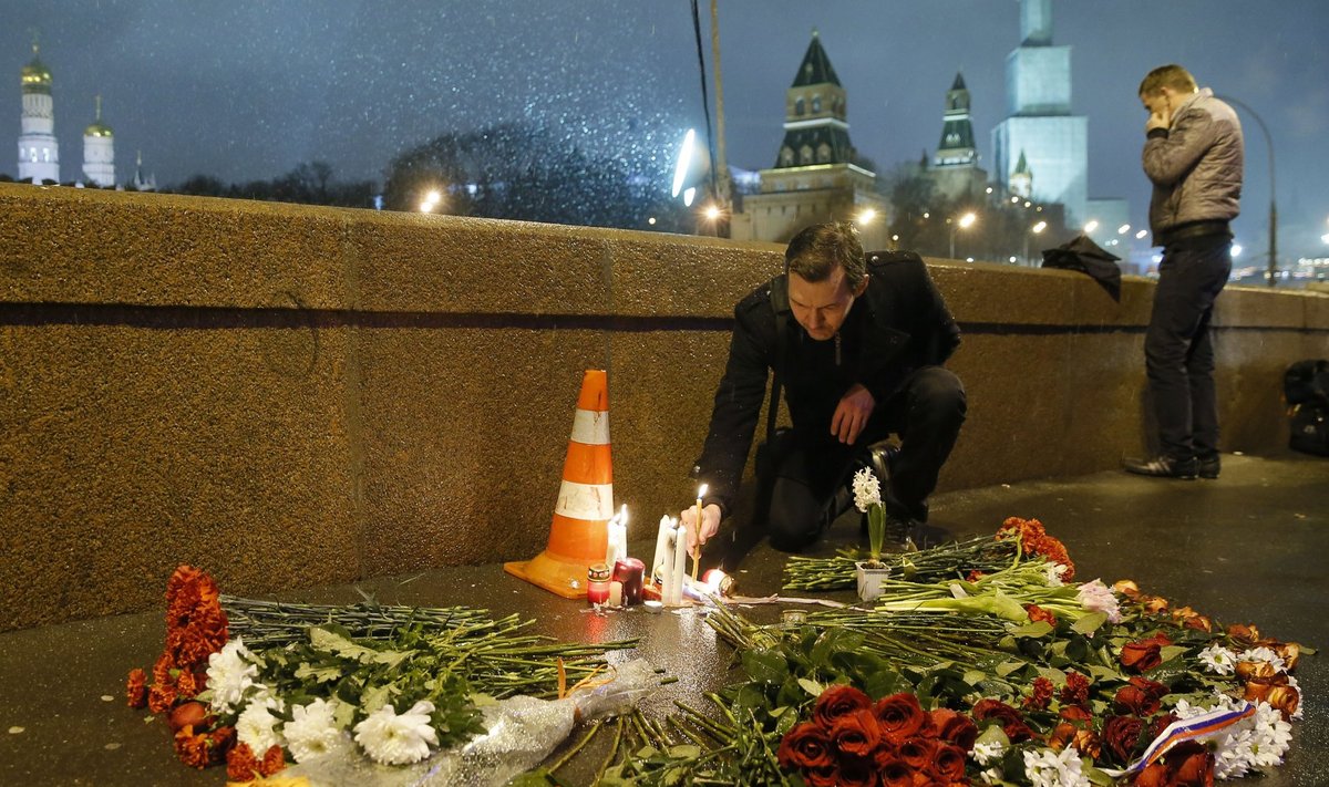 A man places a lit candle at the place where Boris Nemtsov was shot dead near the Kremlin in central Moscow
