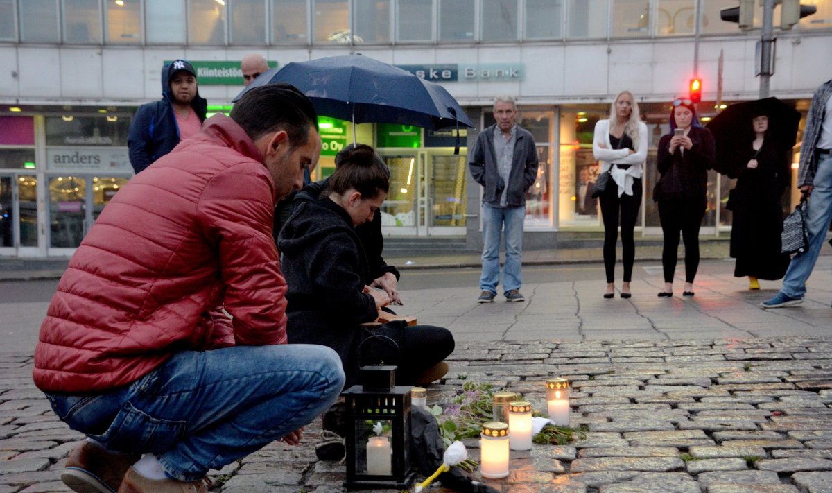 People put candles at the Market Square where several people were stabbed, in Turku