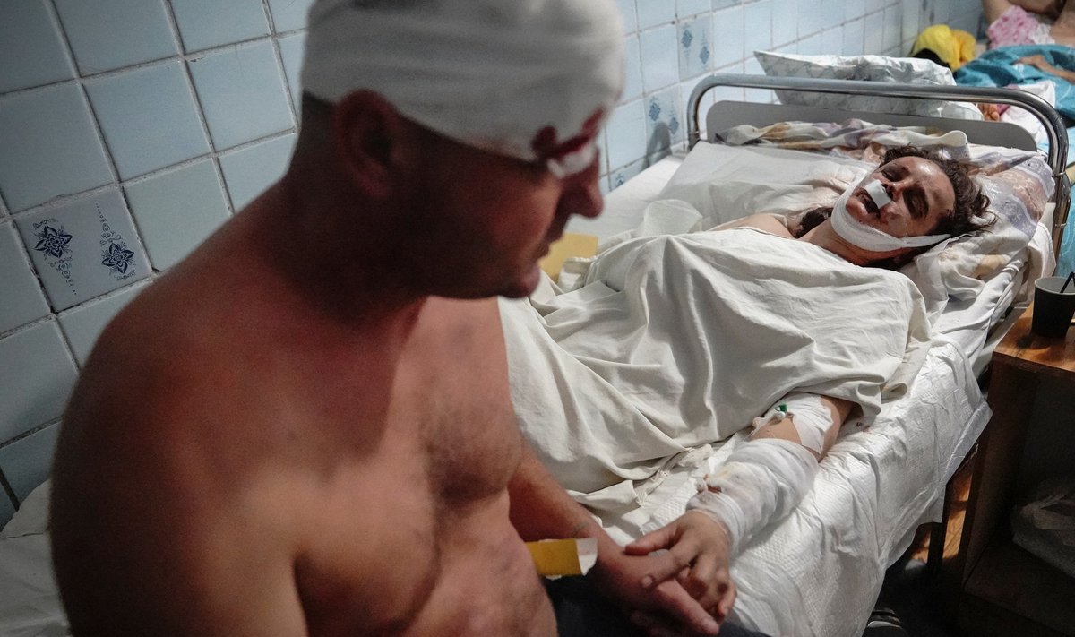 Семейная пара, раненая в торговом центре, пострадавшем от российского ракетного удара, держатся за руки в больнице, Кременчуг, Полтавская область, Украина, 27 июня 2022 г.