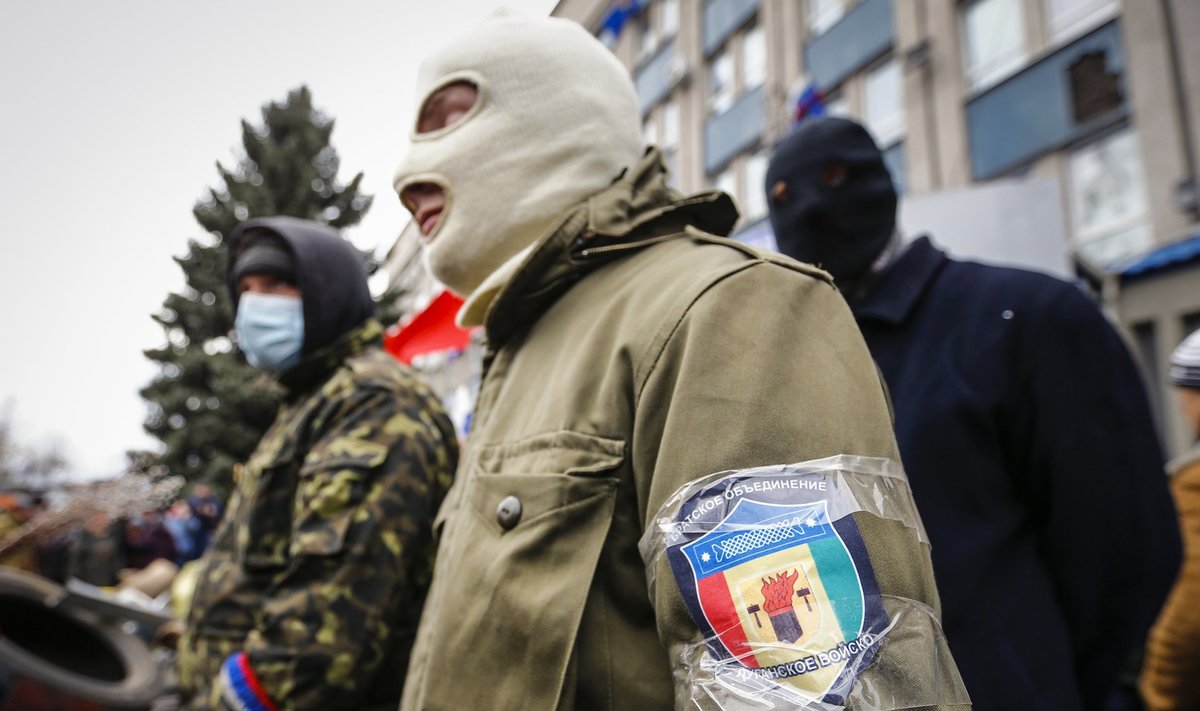 Masked pro-Russian protesters stand guard in front of the seized office of the SBU state security service in Luhansk